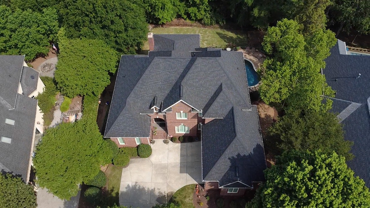 Aerial view of a dark architectural shingle roof on a large brick estate home