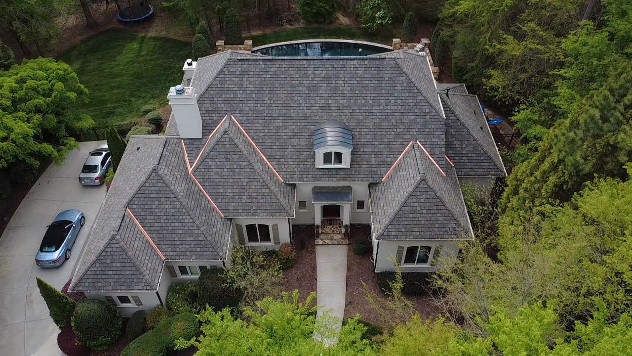 Aerial view of a designer shingle roof with copper-accented rooflines on a luxury residence